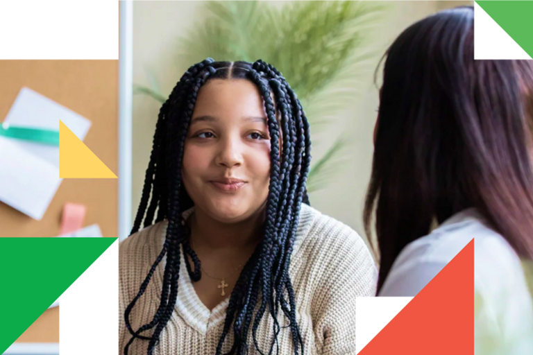 A woman with long braids talking to another woman.